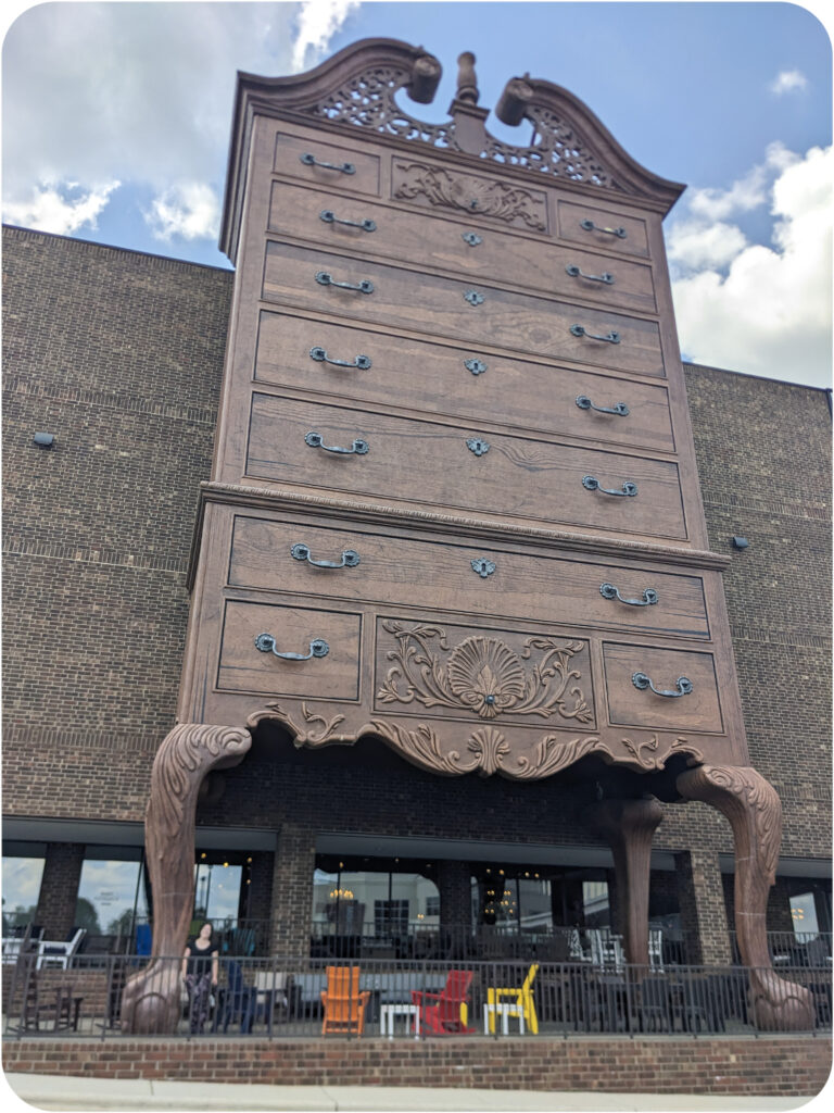 An antique dresser larger than the building to which it is adjacent.